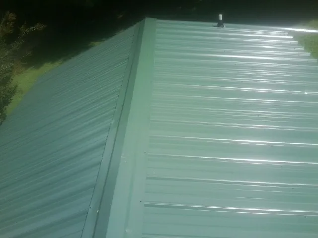 New green metal panels meeting at the ridge of a roof — Flat Roof Repair work by our crew in Jean