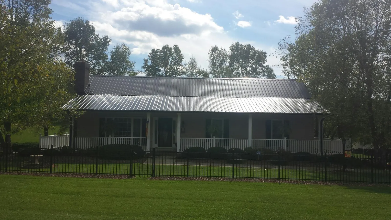 Gray metal roof on a brick ranch with a full width front porch — Gutter Guard Installation work by our crew in Jean